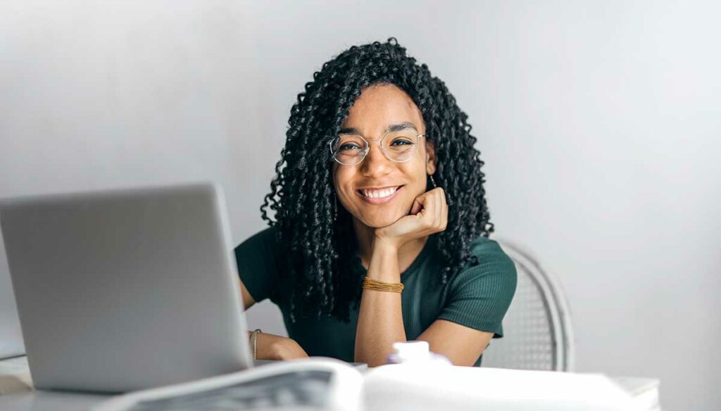 A smiling customer service representative sitting at a desk is ready to take the next call.