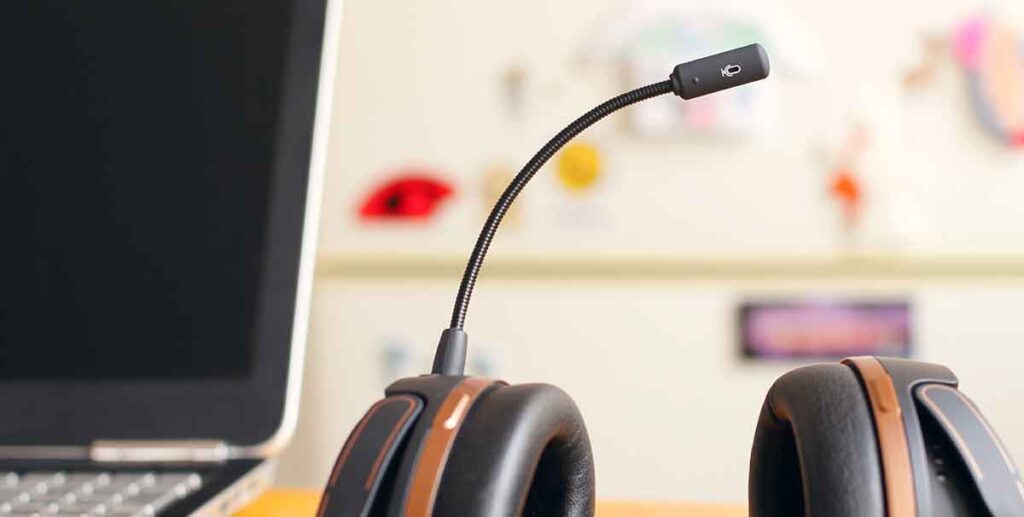 Laptop and headset with microphone sitting on a table.