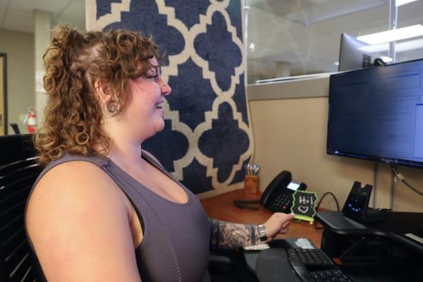 A customer service representative smiles at their computer screen as they talk to an agent from another call center.